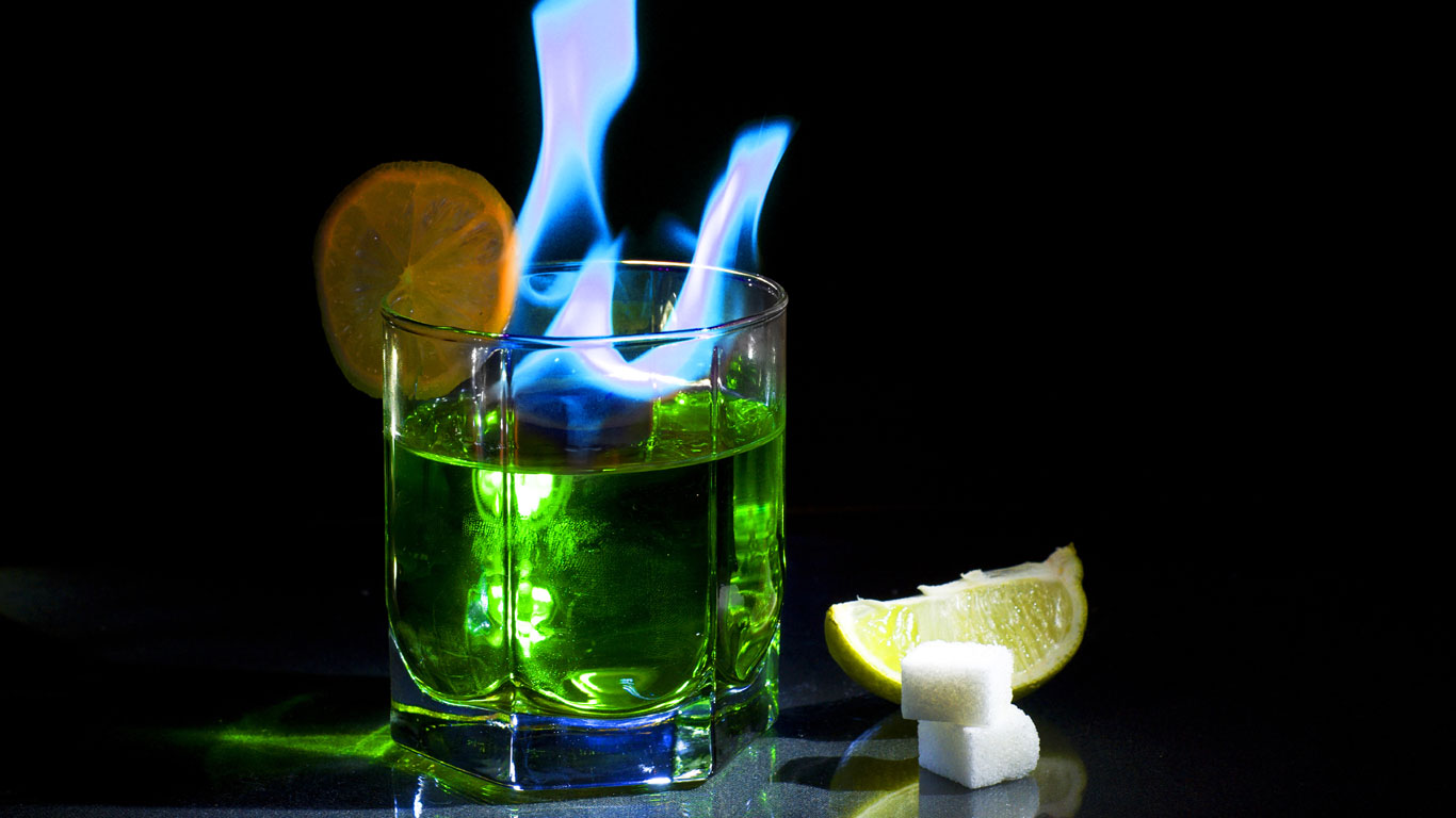 Glas mit Absinth und blauer lodernder Flamme